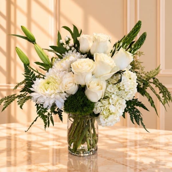 White roses and lilies arranged in a clear glass vase