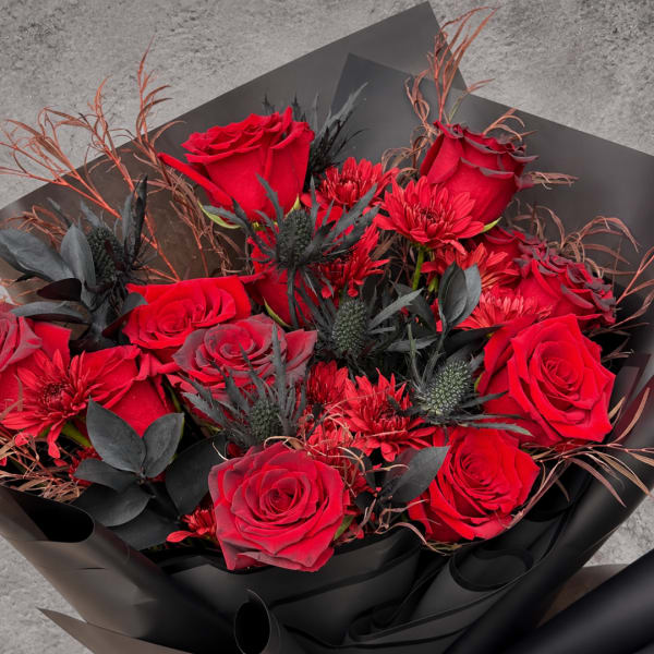 Bouquet of red roses and red chrysanthemums wrapped in black paper