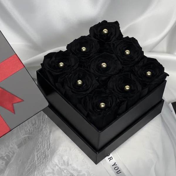 Black roses in a square gift box with a red ribbon bow