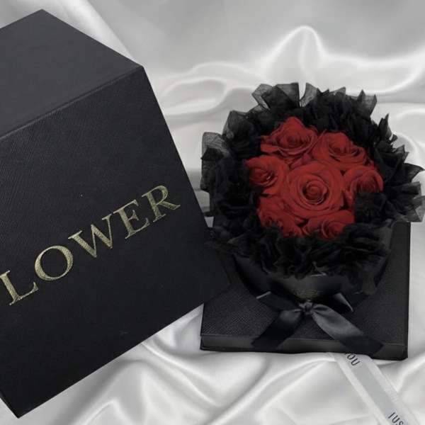 Red roses in a black gift box with black wrapping and ribbon