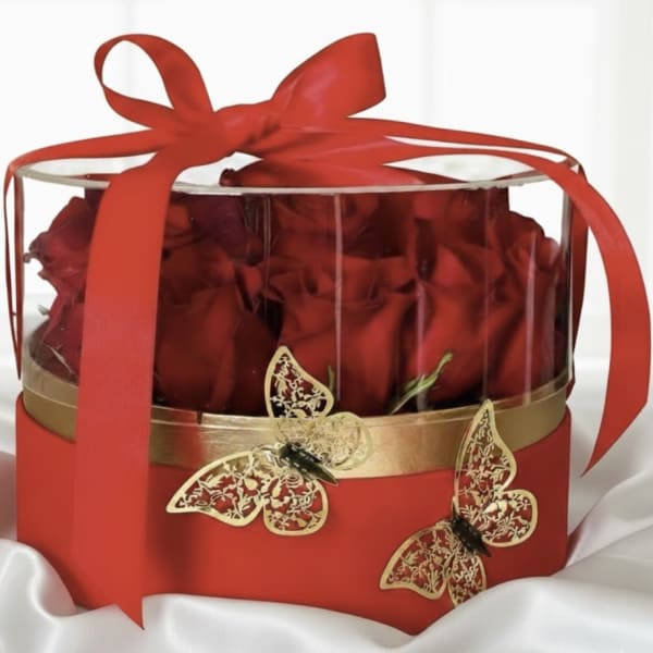Red roses in a clear round gift box tied with a red ribbon