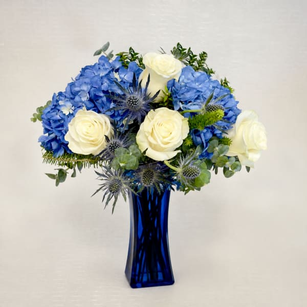 Blue hydrangeas and white roses arranged in a cobalt vase