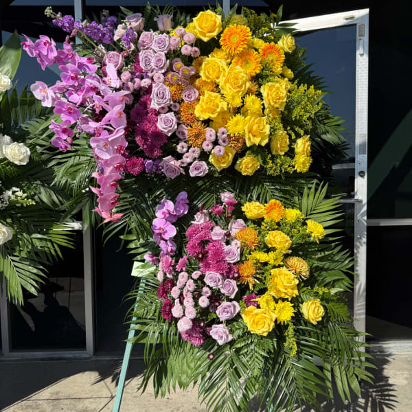 Large standing floral spray with yellow, pink, and purple flowers