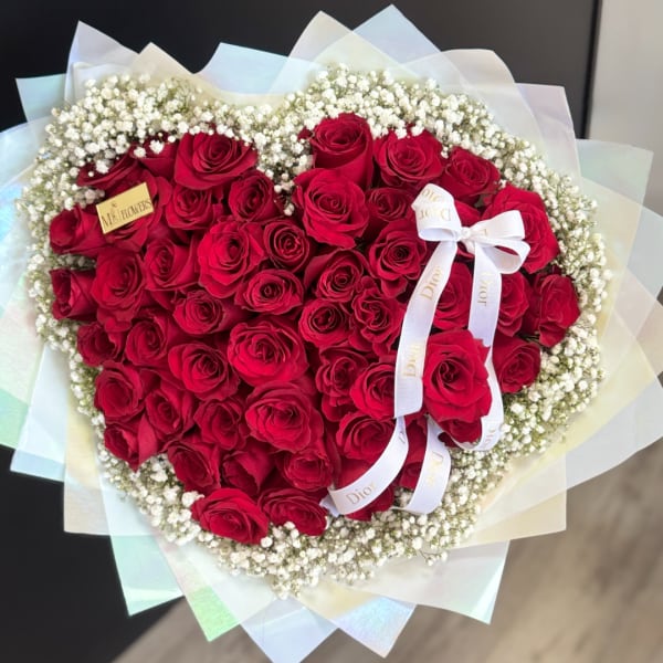 Heart-shaped bouquet of red roses with white baby's breath and a ribbon