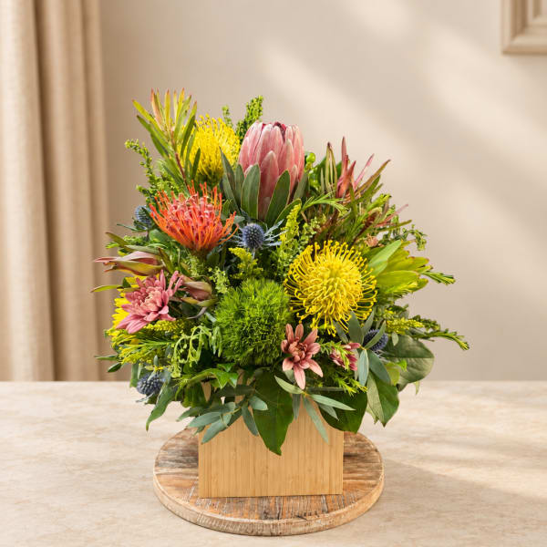 Mixed bouquet in a wooden box with pink, yellow, and orange blooms