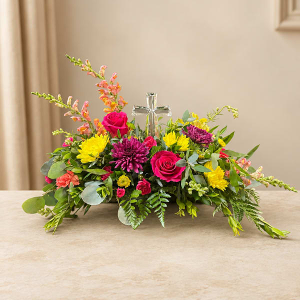 Colorful floral centerpiece with roses, chrysanthemums, and a glass cross
