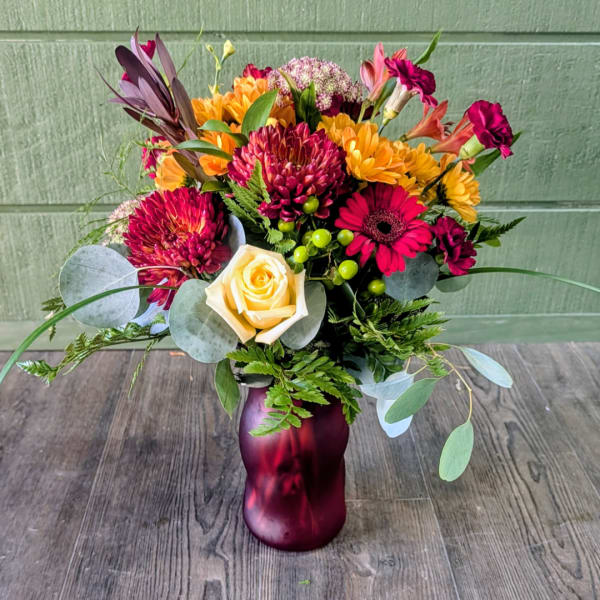 Mixed bouquet of bright flowers in a purple vase
