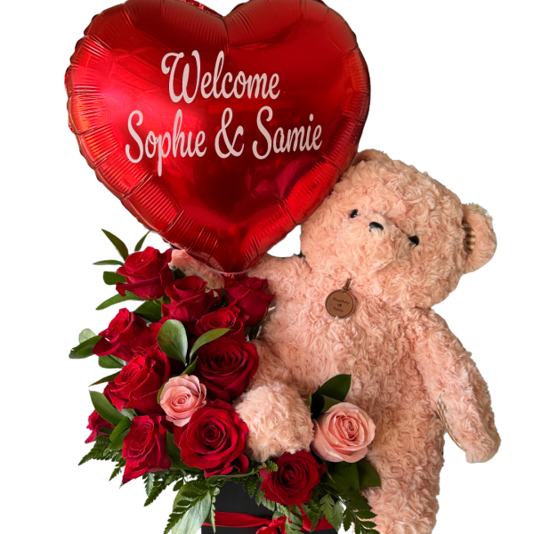 Teddy bear holding a red heart balloon above red and pink roses