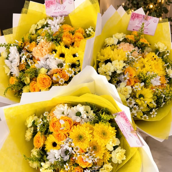 Three yellow and white mixed flower bouquets wrapped in paper