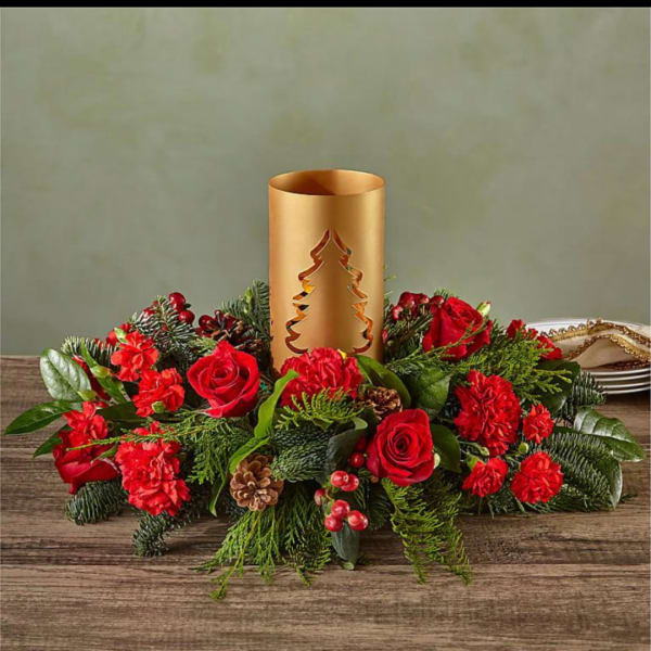 Red roses and carnations arranged around a gold candle holder centerpiece