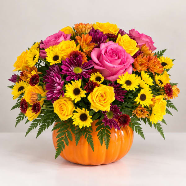 Mixed bouquet in an orange pumpkin container with pink and yellow flowers