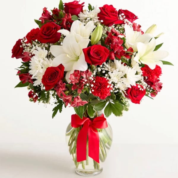 Red roses and white lilies in a glass vase with a red ribbon
