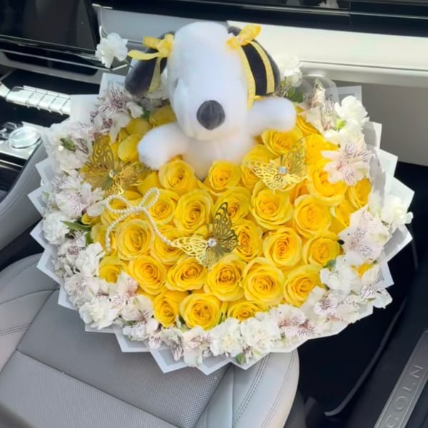 Yellow rose bouquet with a plush Snoopy topper and white flowers