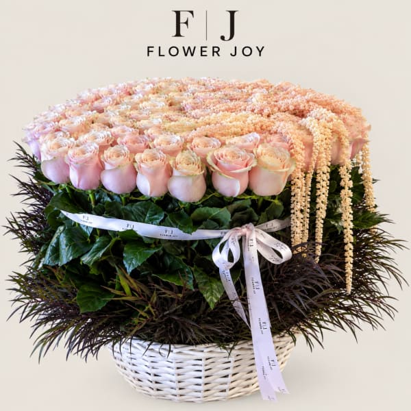 Large pastel rose arrangement in a white basket with ribbon
