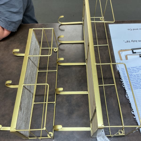 Gold metal display racks on a table with papers nearby