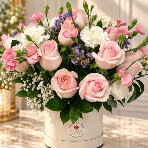 Pink roses and carnations arranged in a white hat box