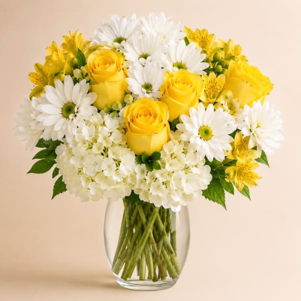Yellow roses and white daisies in a clear glass vase