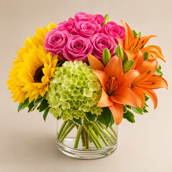 Bouquet of pink roses, sunflowers, green hydrangea, and orange lilies in a glass vase