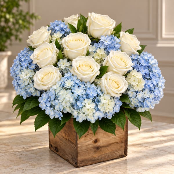 White roses and blue hydrangeas arranged in a wooden box