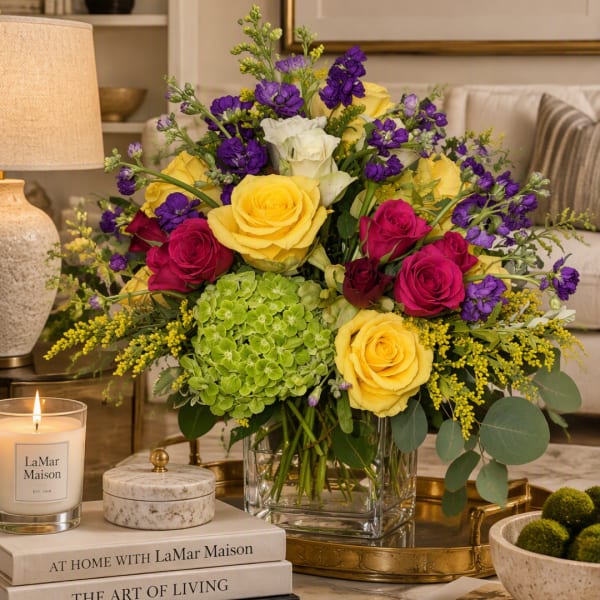 Mixed bouquet of yellow, pink, white, and purple flowers in a glass vase