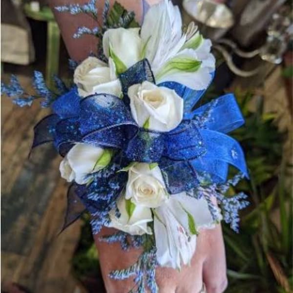 White roses and lilies with blue ribbon on a wrist corsage