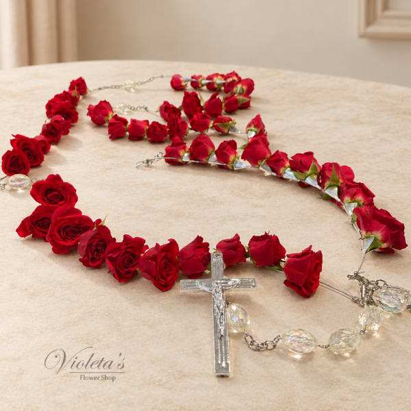 Red rose rosary with clear crucifix and bead accents on a table.