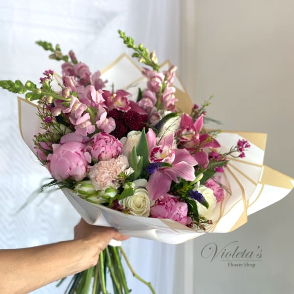 Handheld bouquet of pink and white flowers wrapped in white paper