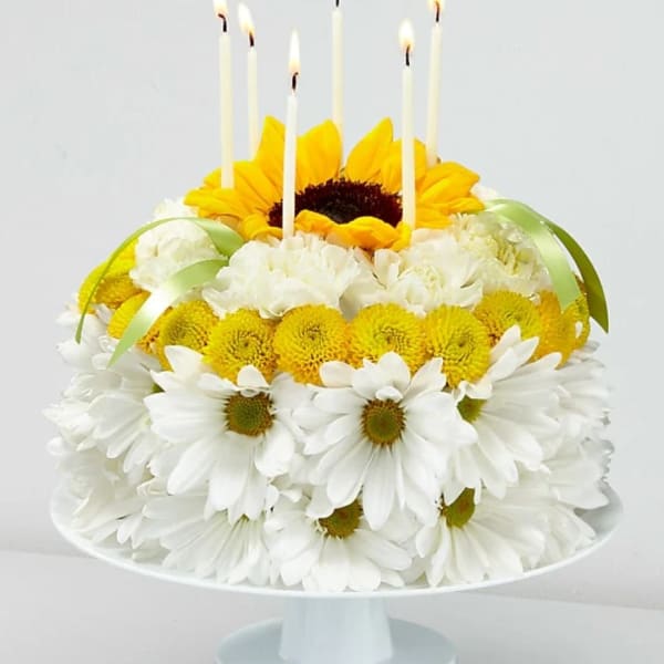 Sunflower and white daisy arrangement with lit taper candles on a pedestal stand