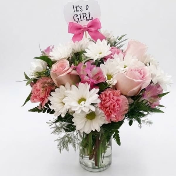 Pink and white bouquet in a glass vase with an "It's a Girl" topper