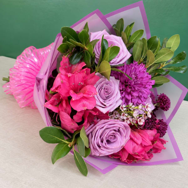 Bouquet of pink and lavender flowers wrapped in purple paper