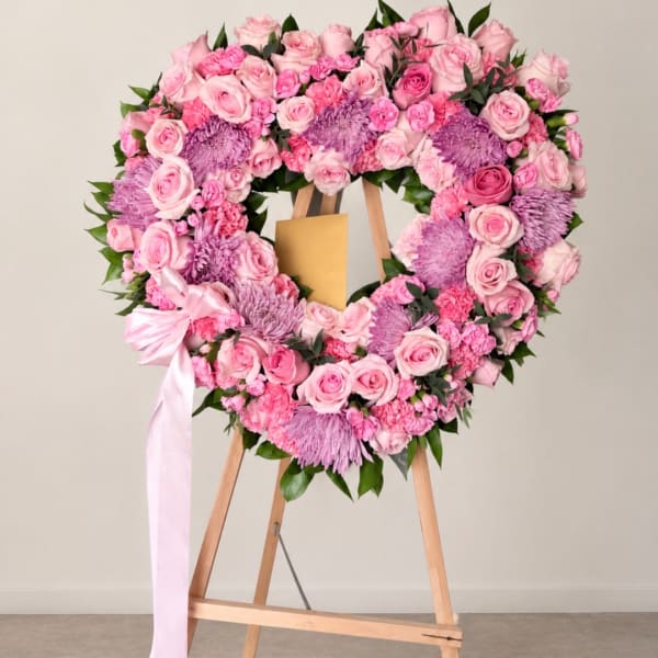Pink and lavender floral heart wreath on a wooden easel with a ribbon bow.