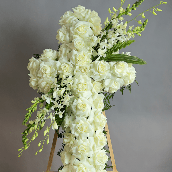 White rose cross on a wooden stand with trailing white flowers