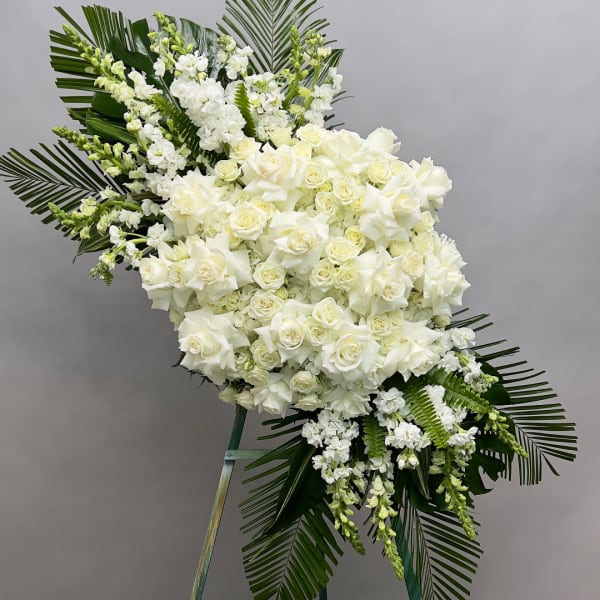 Large white floral standing spray with roses and lilies on an easel