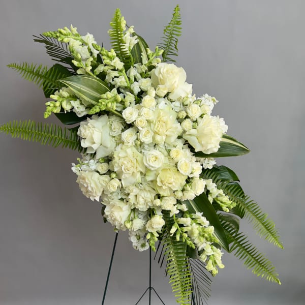 Large white floral standing spray with roses and lilies on a metal easel