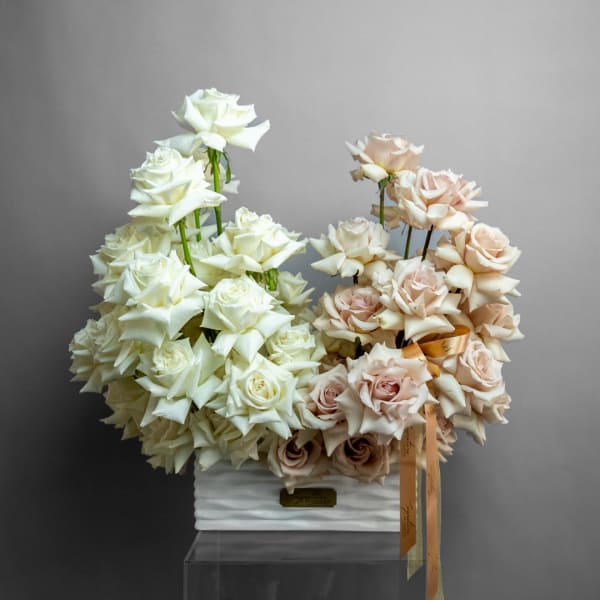 Arrangement of white and blush roses in a white rectangular vase