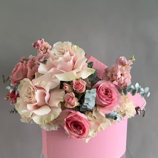 Pink and white roses arranged in a pink box