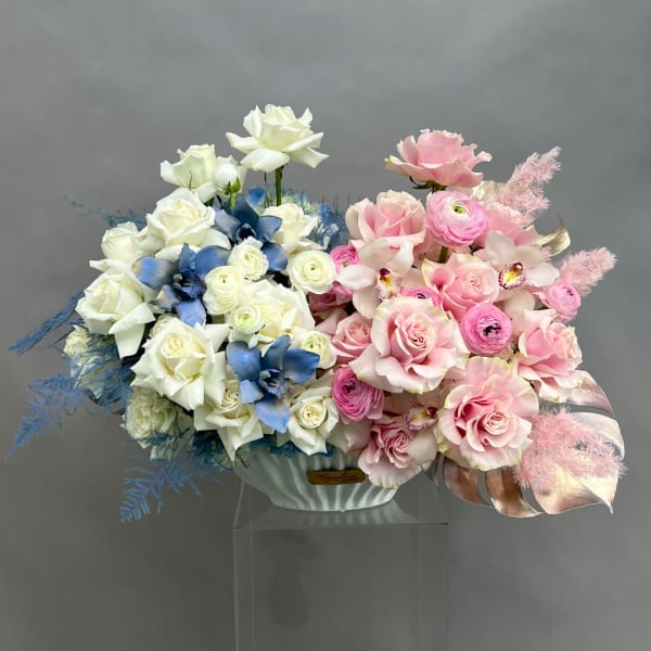 Pink and white rose arrangement with blue flowers in a white vase
