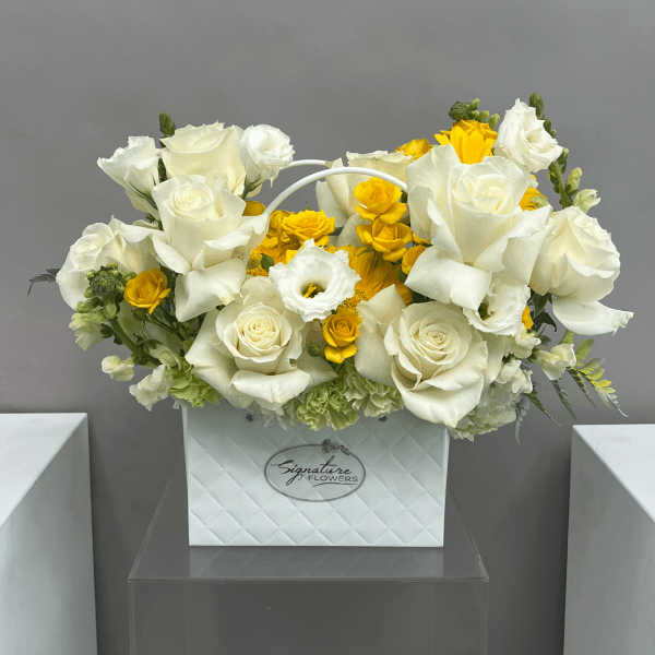 White and yellow rose arrangement in a white box vase