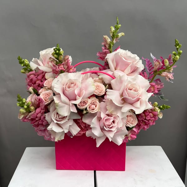 Pink and white rose arrangement in a bright pink handled box