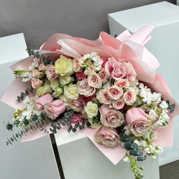 Pink and white rose bouquet wrapped in pale pink paper
