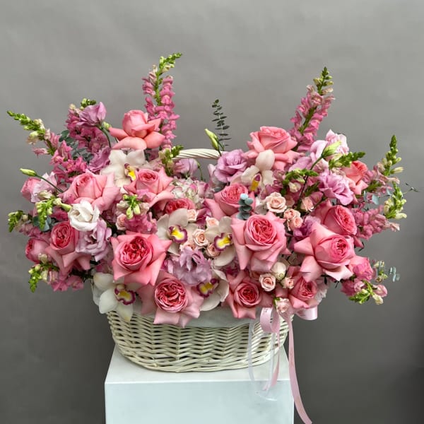 Pink rose and orchid arrangement in a white basket