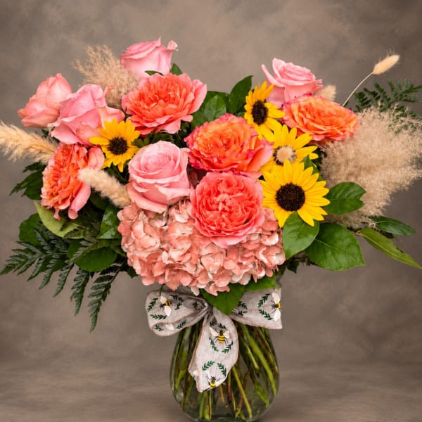 Pink and coral bouquet with sunflowers in a glass vase