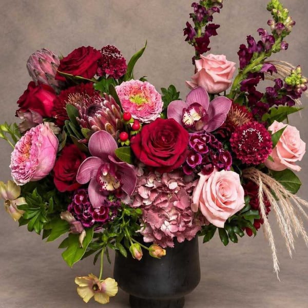 Mixed bouquet of roses, orchids, and pink hydrangea in a black vase