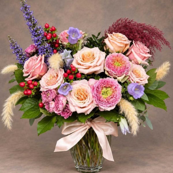 Mixed pink and peach bouquet in a glass vase with a satin ribbon