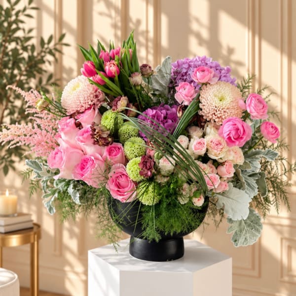 Large pink and lavender floral arrangement in a black vase