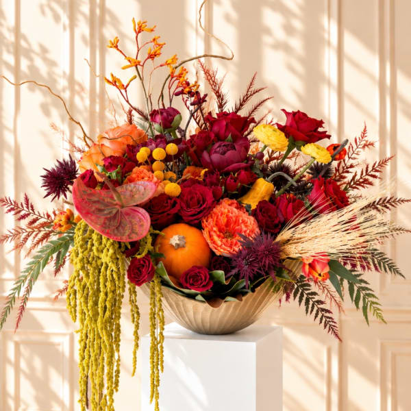 Autumn floral arrangement with roses and pumpkins in a bowl vase