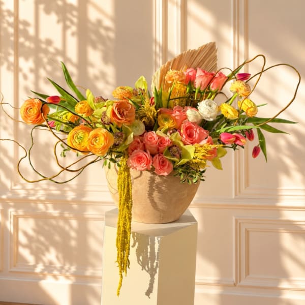 Colorful floral arrangement in a beige vase on a pedestal