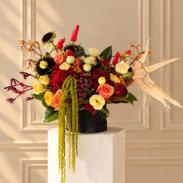 Colorful mixed bouquet in a black round box with trailing greenery