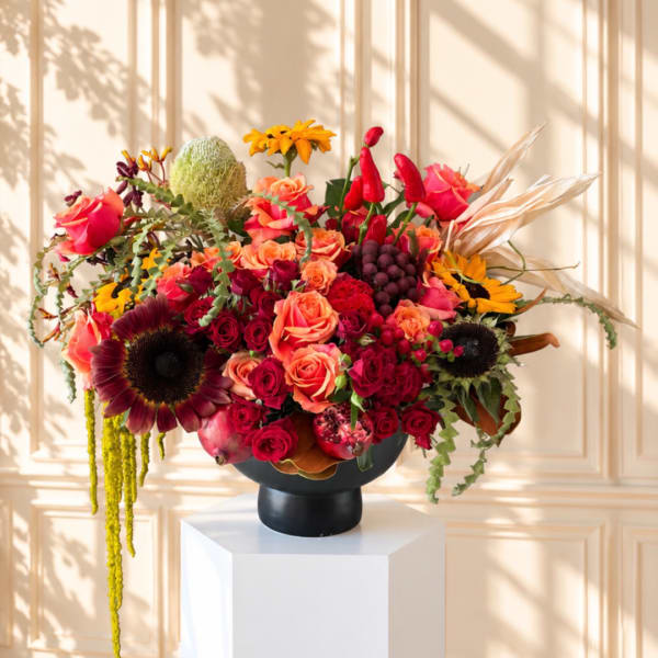 Colorful mixed bouquet in a black vase with roses and sunflowers