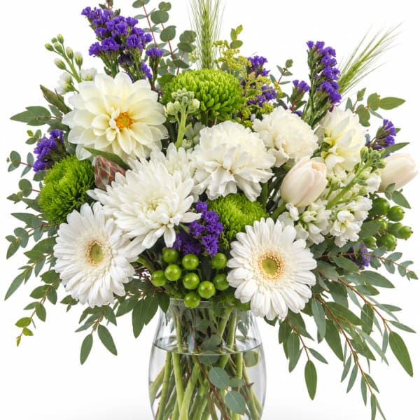 White and green mixed bouquet in a clear glass vase with purple accents